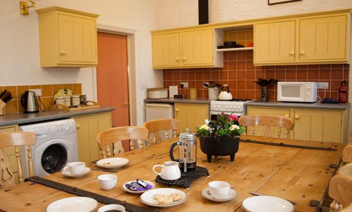 Open plan kitchen dining room with original wood features, ceramic hob cooker, fridge, freezer and pantry